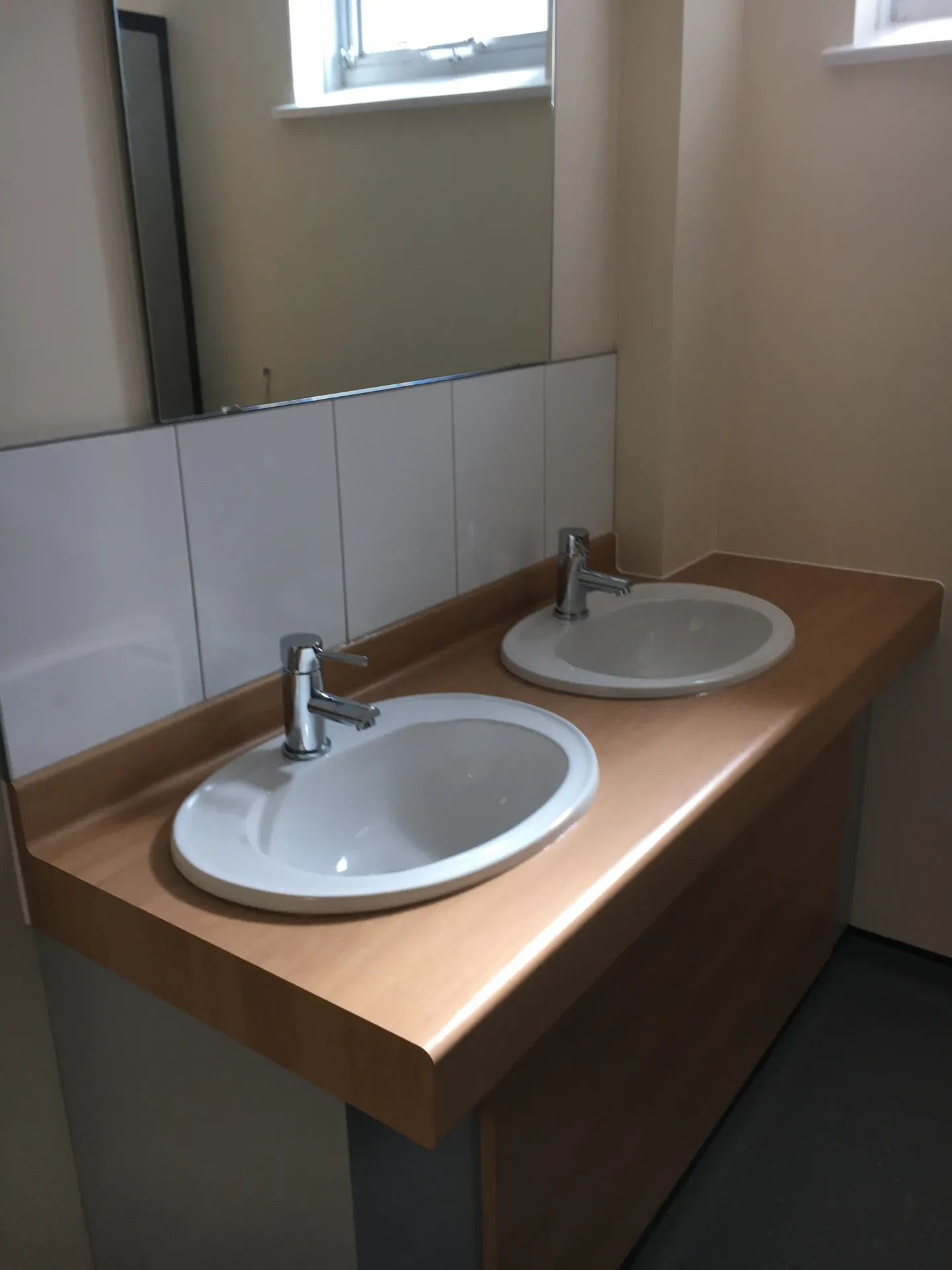 Twin wash basins with mirror and wood counter
